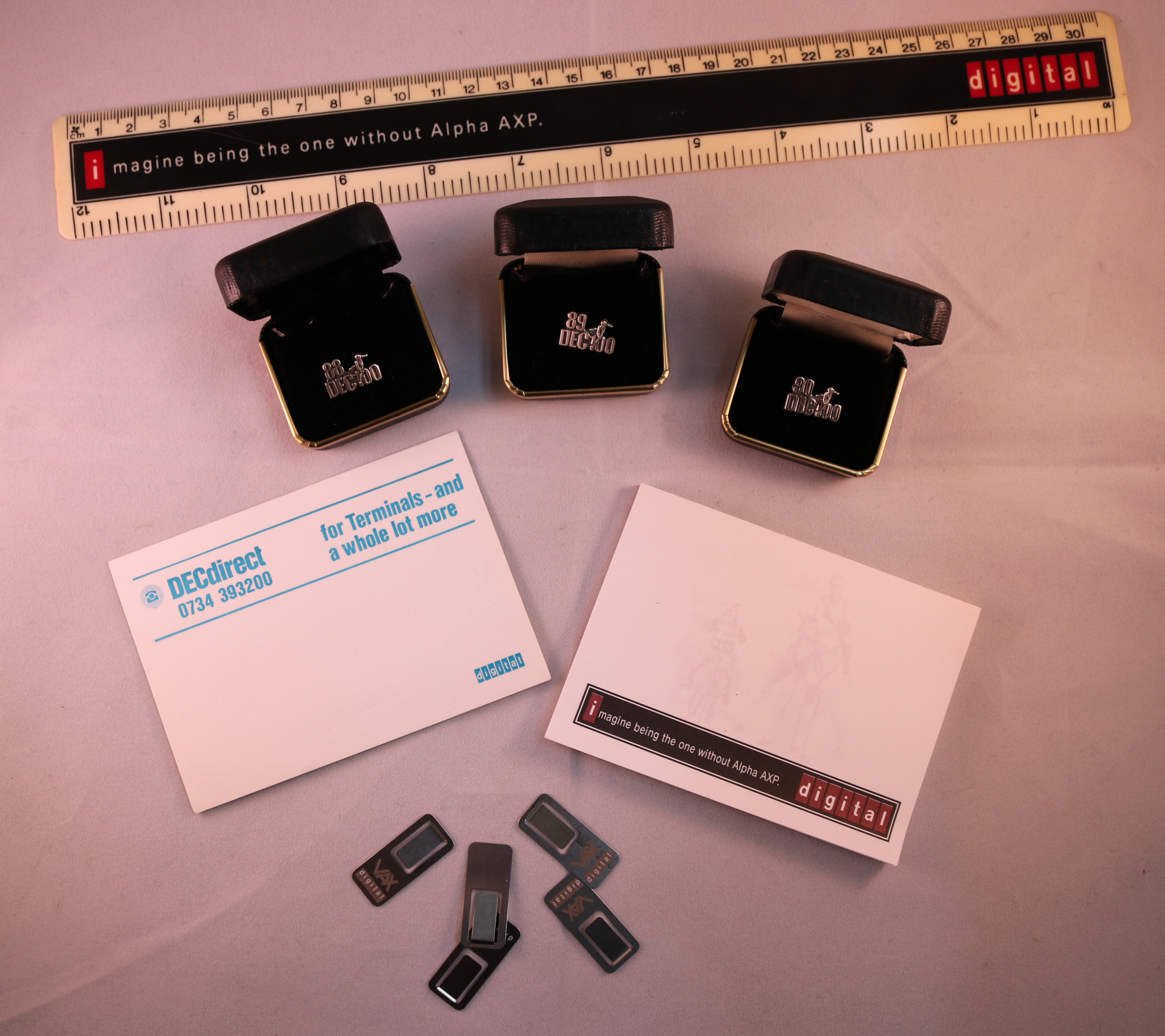 a selection of DEC marketing materials, including a ruler, pads of paper, marathon pins